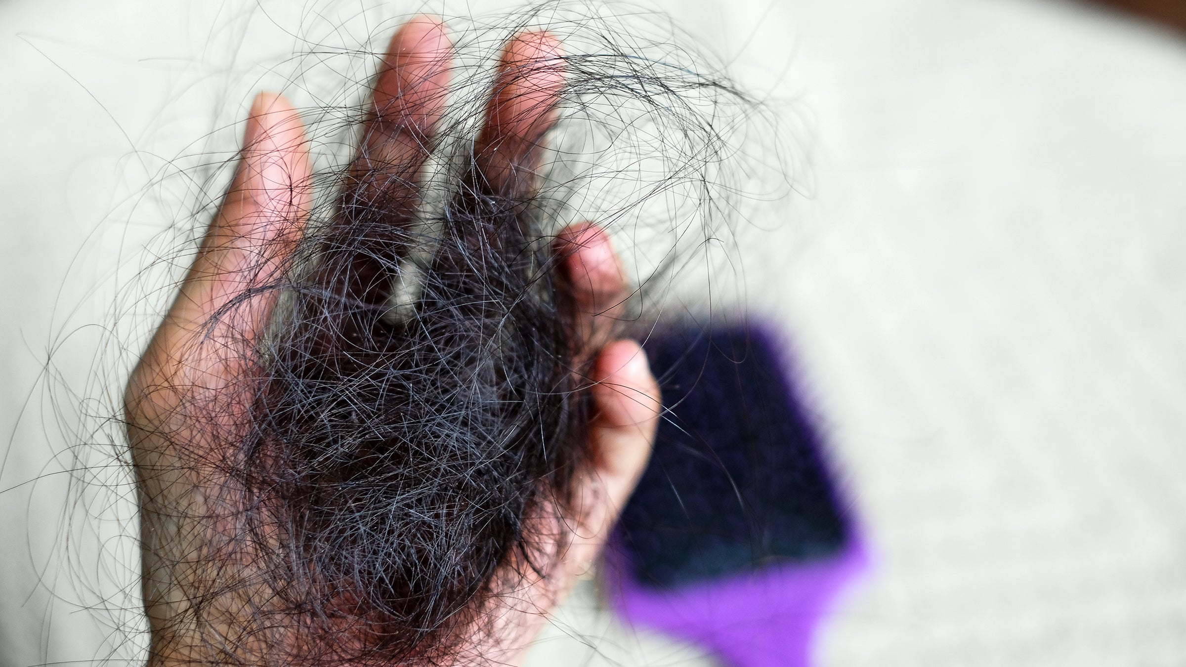 closeup of hand holding fallen out heair above a bin